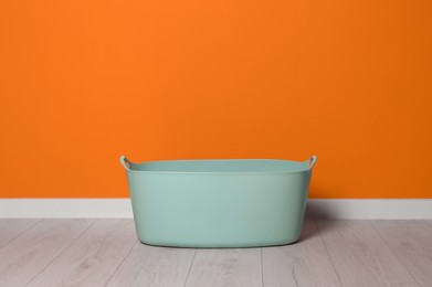 Laundry basket with handles near orange wall indoors, space for text