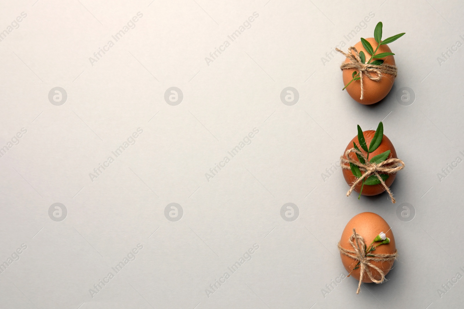 Photo of Festively decorated chicken eggs on light grey background, flat lay with space for text. Happy Easter