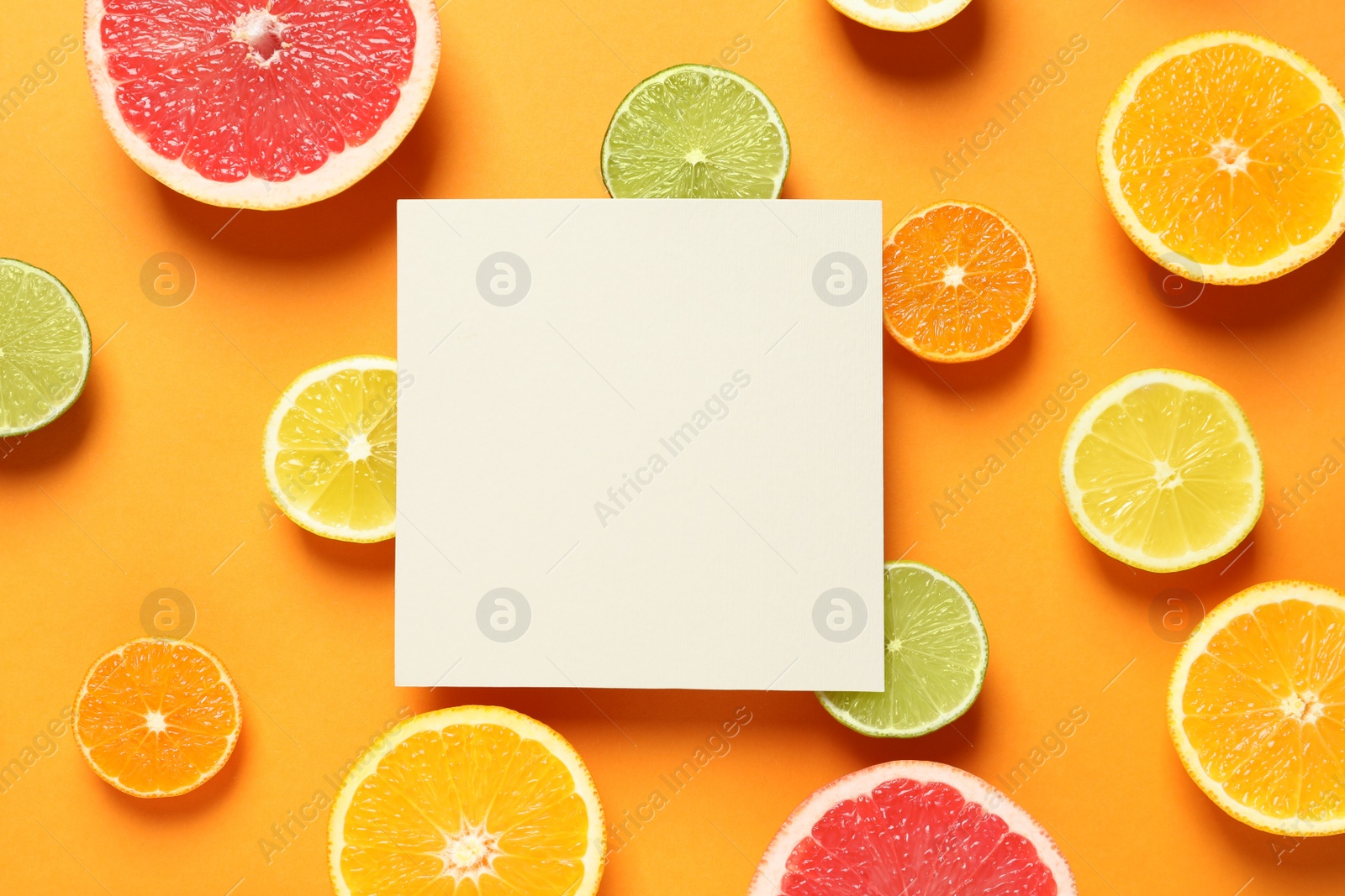 Photo of Fresh citrus fruits and blank card on color background, flat lay. Space for text