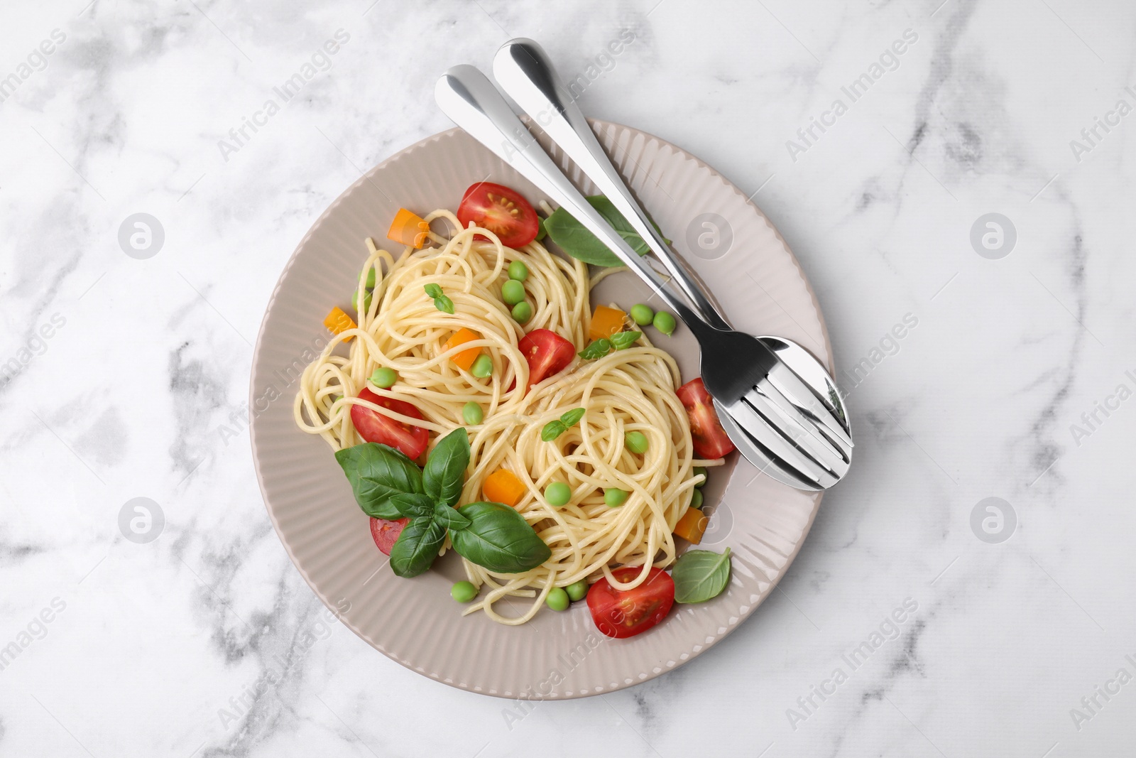 Photo of Plate of delicious pasta primavera and cutlery on white marble table, top view