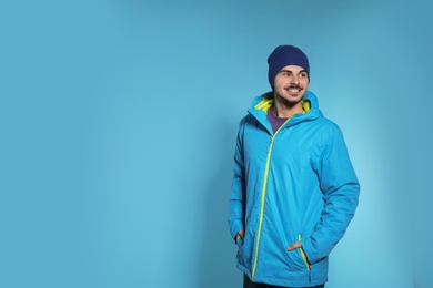 Photo of Young man wearing warm clothes on color background, space for text. Ready for winter vacation