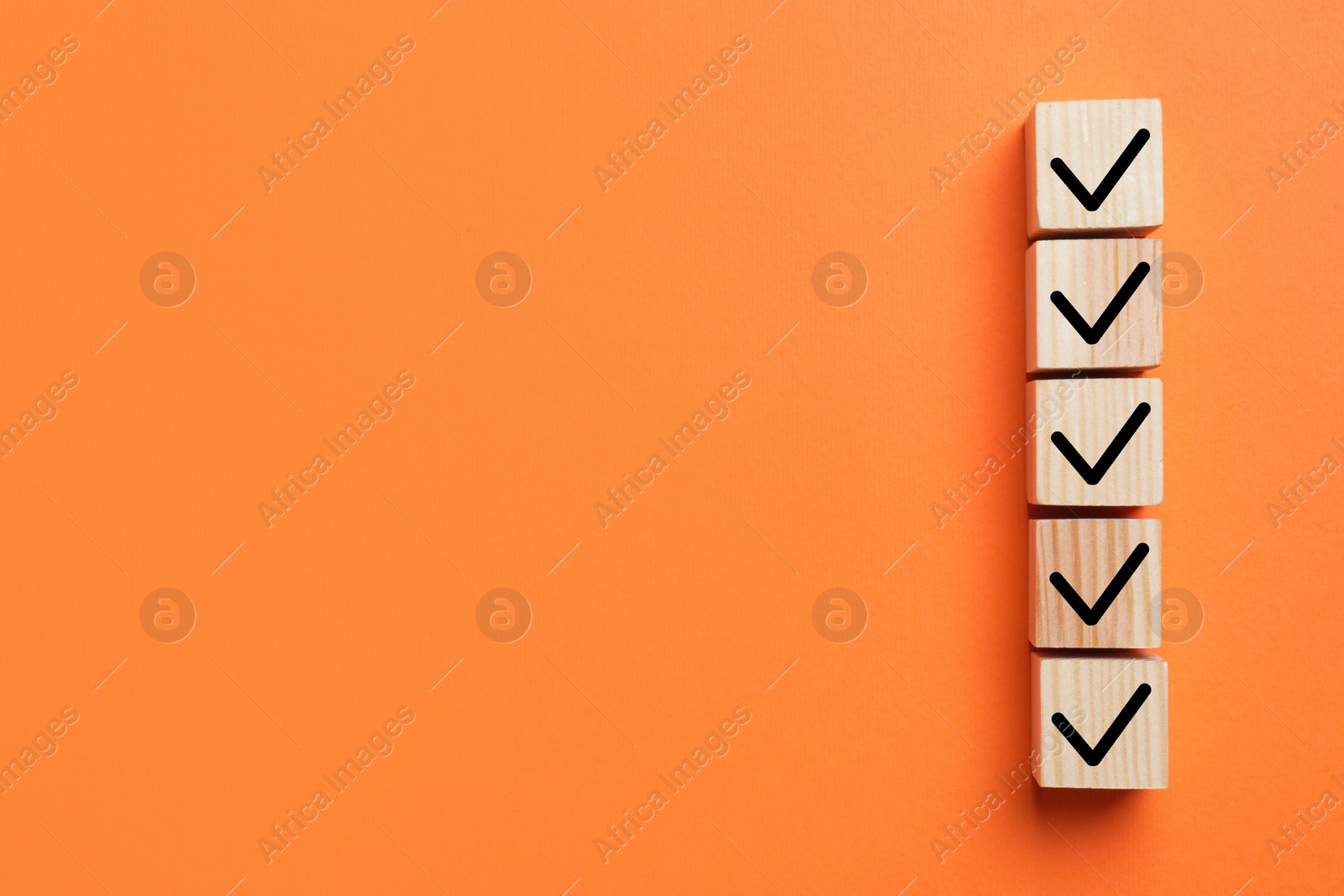 Image of Wooden cubes with check marks on orange background, top view. Space for text