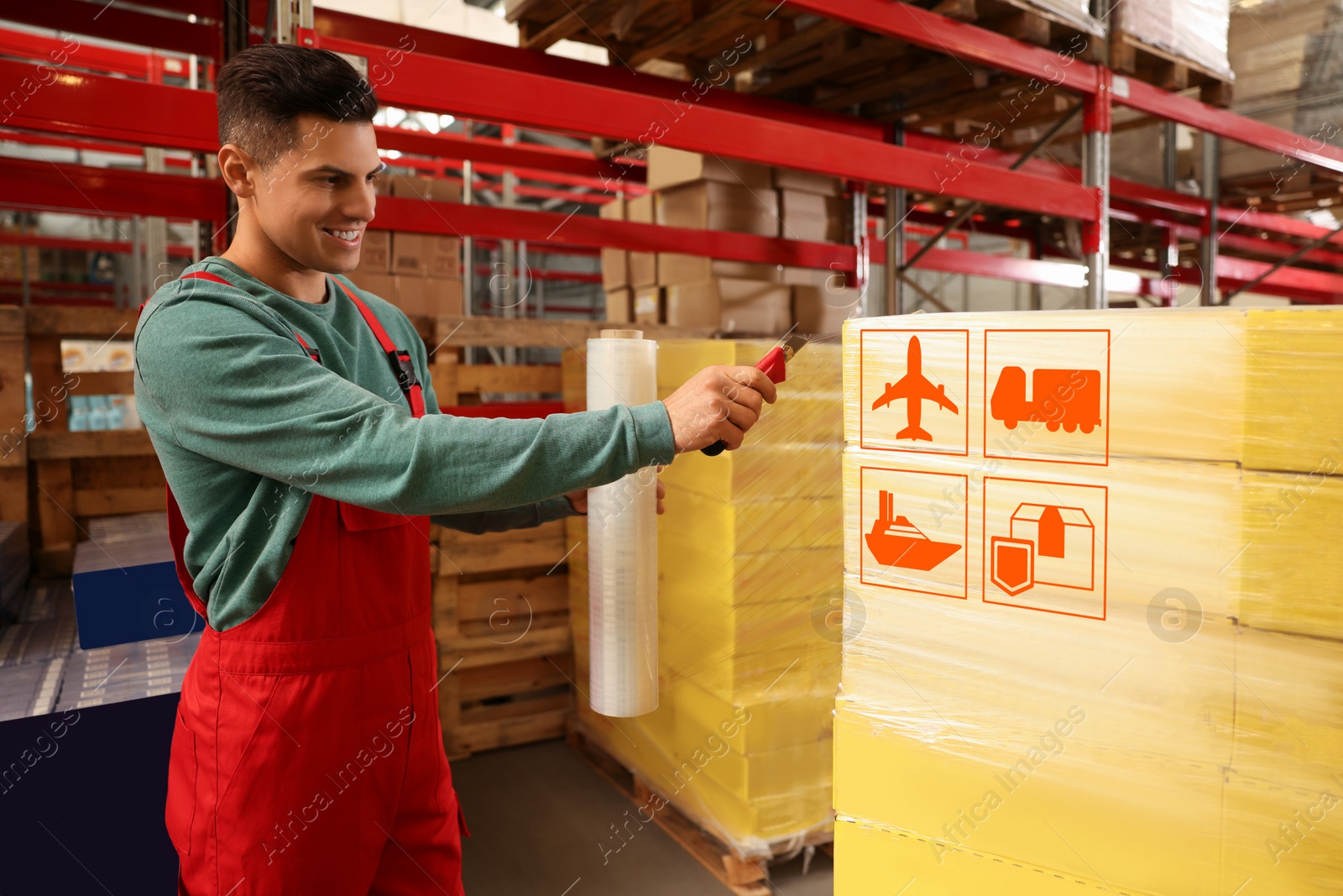 Image of Worker wrapping boxes with shipping icons in stretch film at warehouse