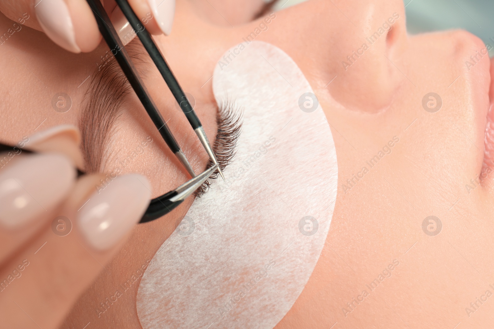 Photo of Young woman undergoing eyelash extension procedure, closeup