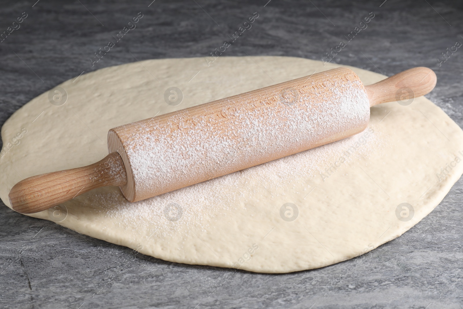 Photo of Raw dough and rolling pin on grey table