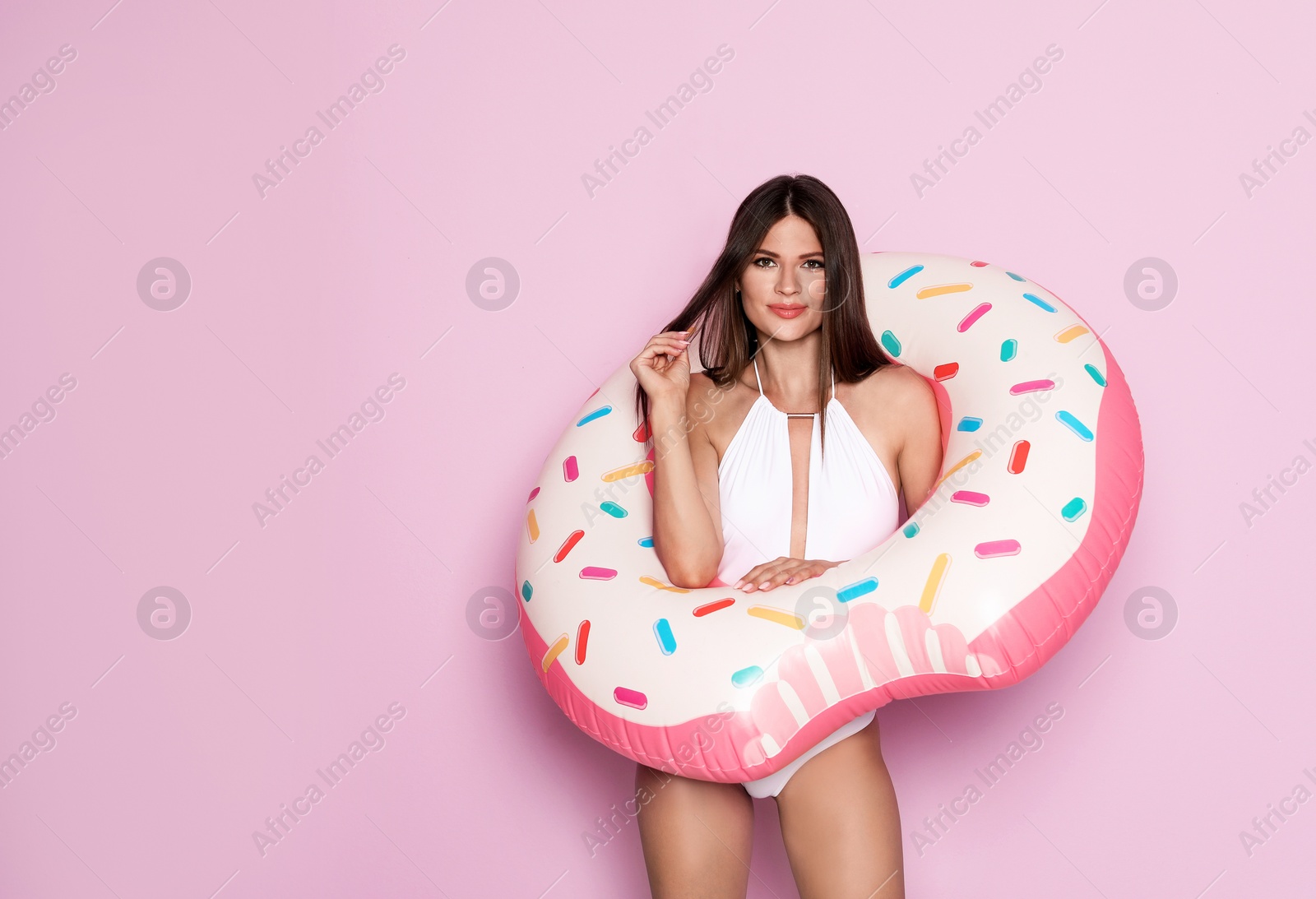 Photo of Sexy young woman in bikini with inflatable ring on color background