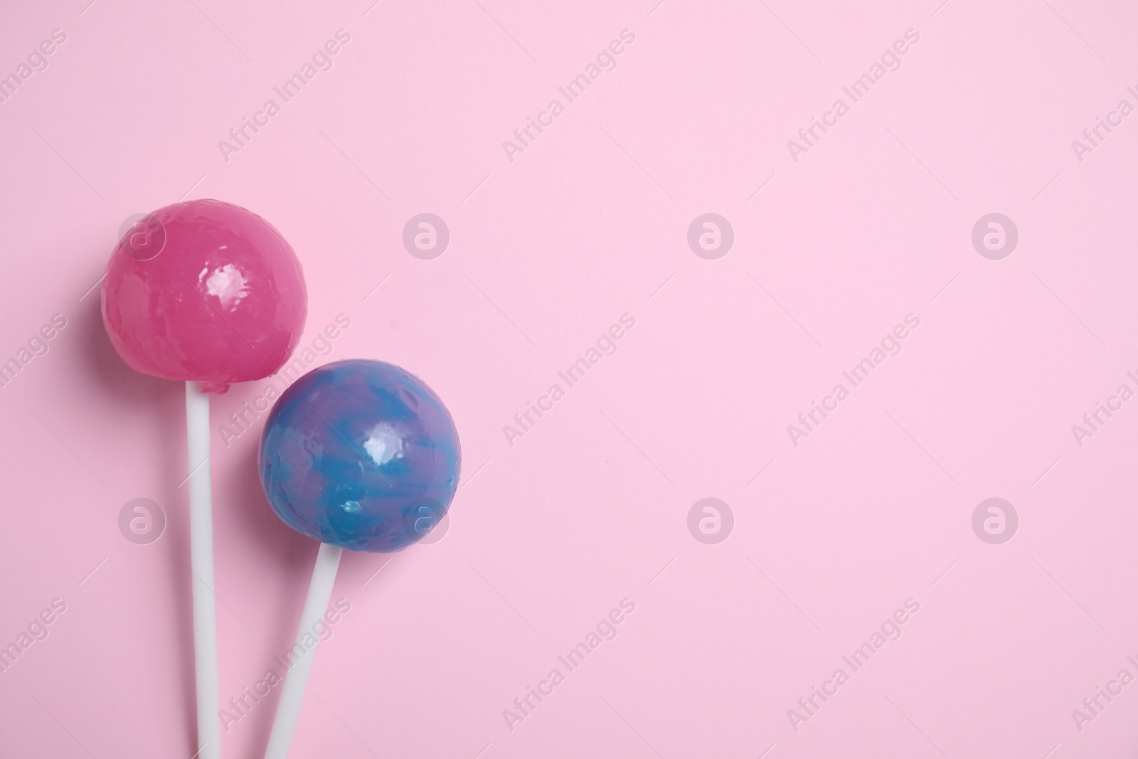 Photo of Sticks with colorful lollipops on pink background, flat lay. Space for text