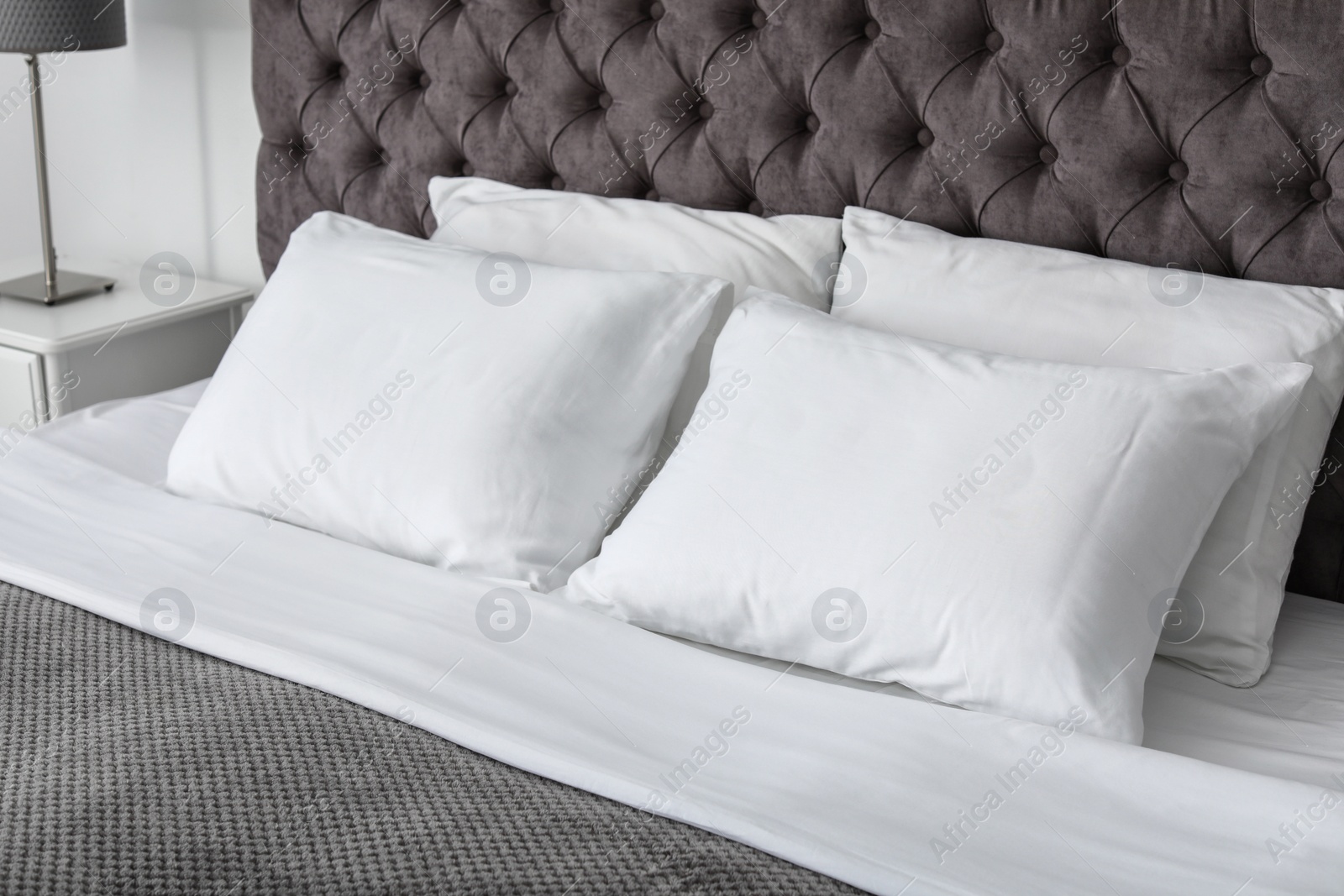 Photo of Soft white pillows on comfortable bed indoors