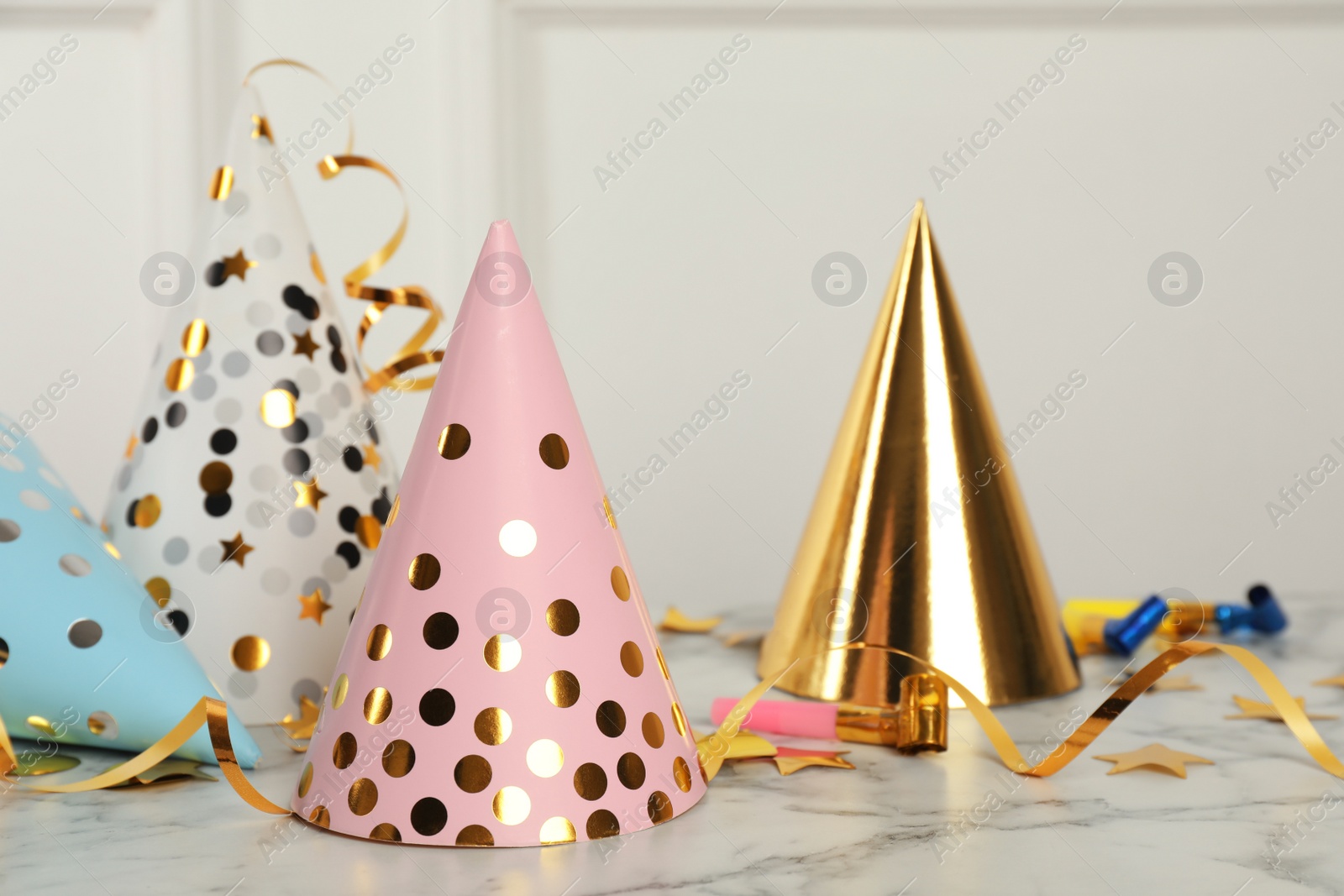 Photo of Party hats and festive items on marble table near white wall indoors