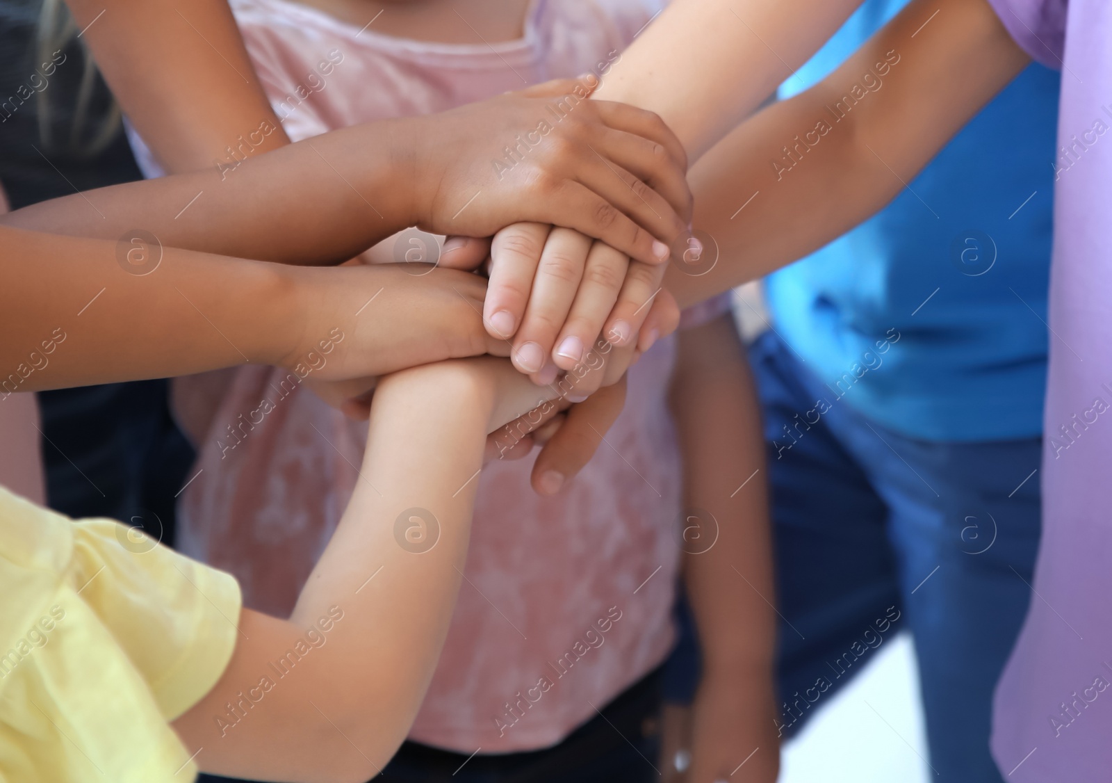 Photo of Little children putting their hands together, indoors. Unity concept