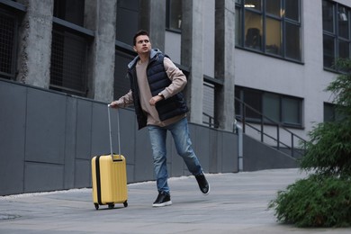 Being late. Worried man with yellow suitcase running outdoors