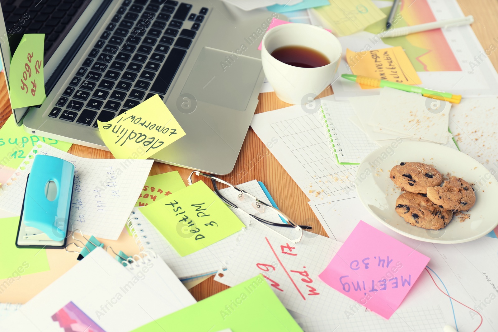 Photo of Messy table with laptop and cookies. Concept of being overwhelmed by work