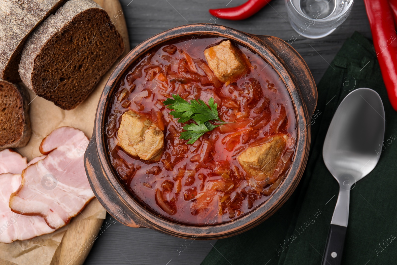 Photo of Tasty borscht in bowl served on grey wooden table, flat lay