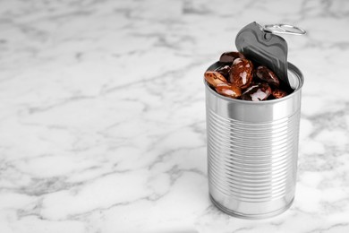 Photo of Tin can with kidney beans on white marble table, space for text