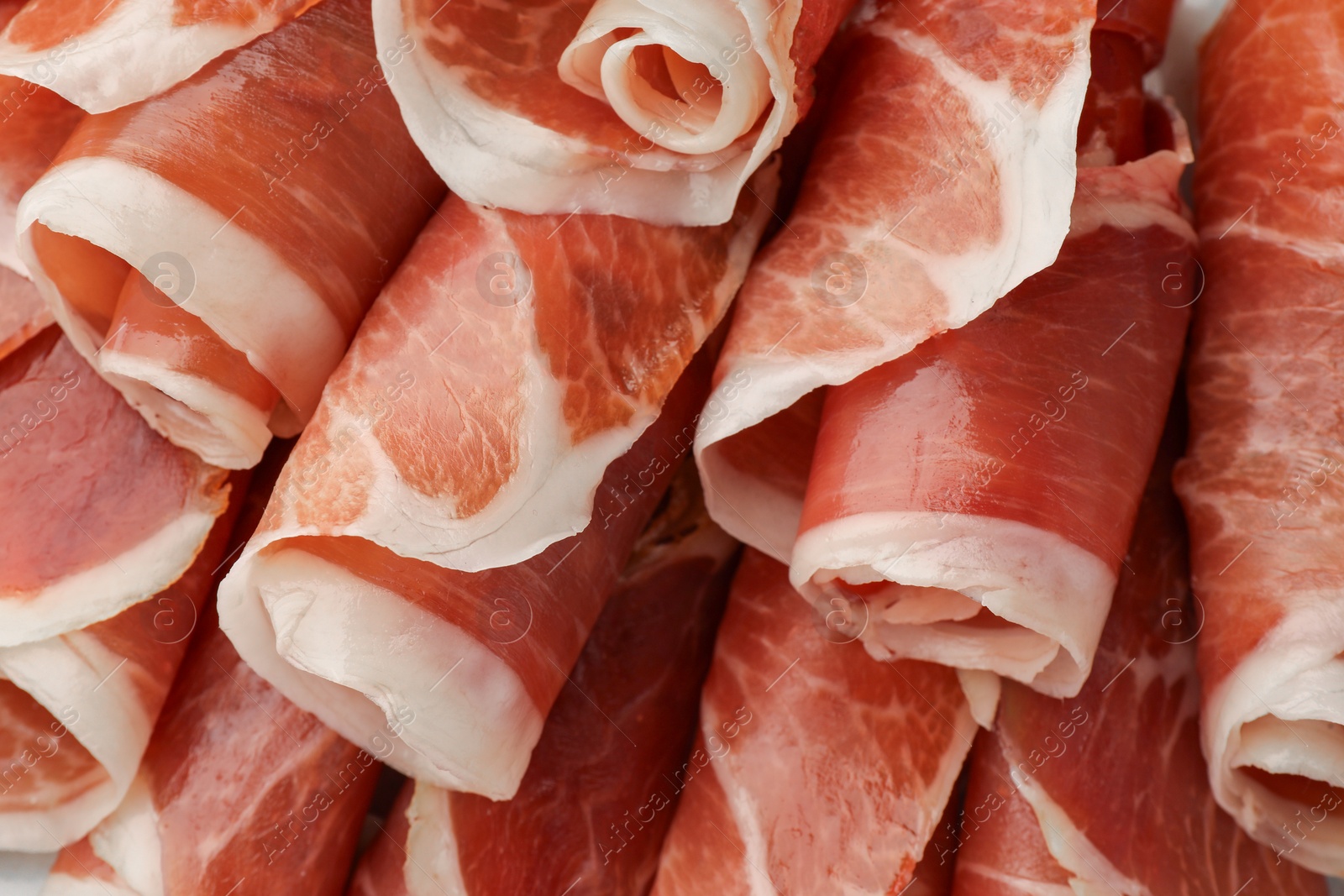 Photo of Rolled slices of delicious jamon as background, closeup