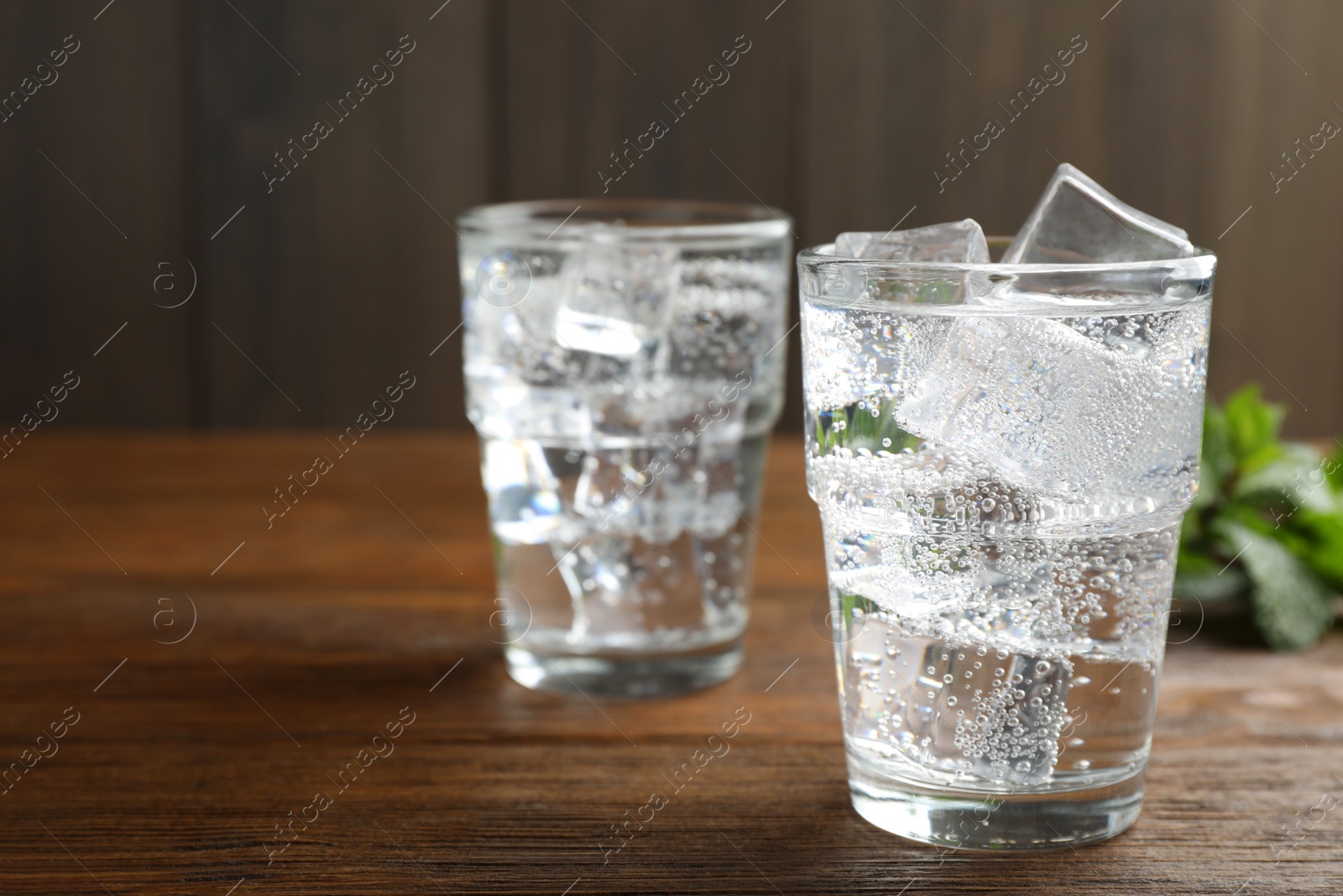 Photo of Glasses of soda water with ice on wooden table. Space for text