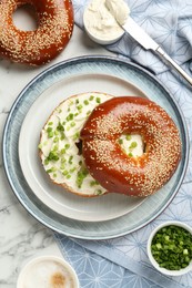 Photo of Delicious bagel with cream cheese and green onion on white marble table, flat lay