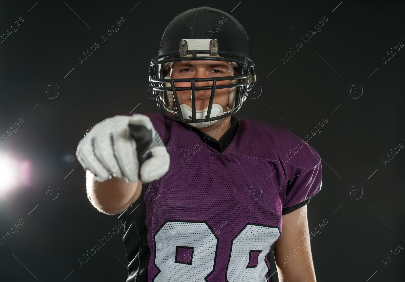 Photo of American football player wearing uniform on dark background