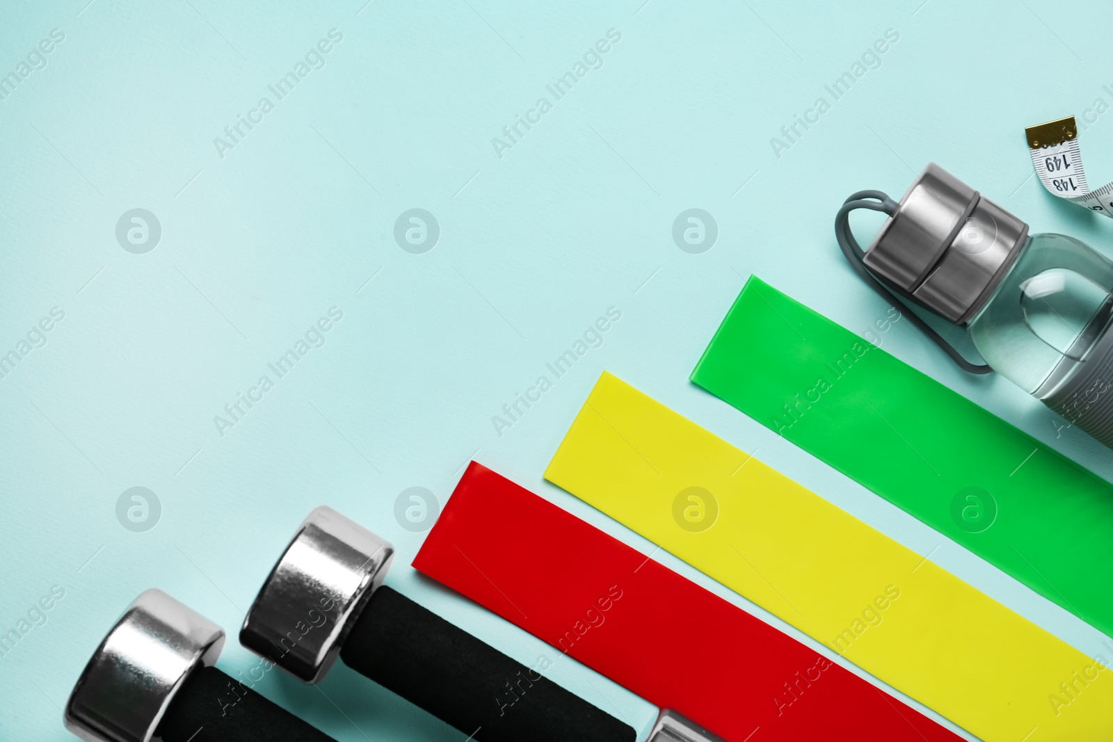 Photo of Flat lay composition with fitness elastic bands on light blue background. Space for text