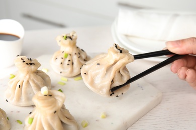 Woman eating tasty baozi dumplings at table, closeup