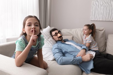 Photo of Cute little children putting funny glasses on father while he sleeping at home