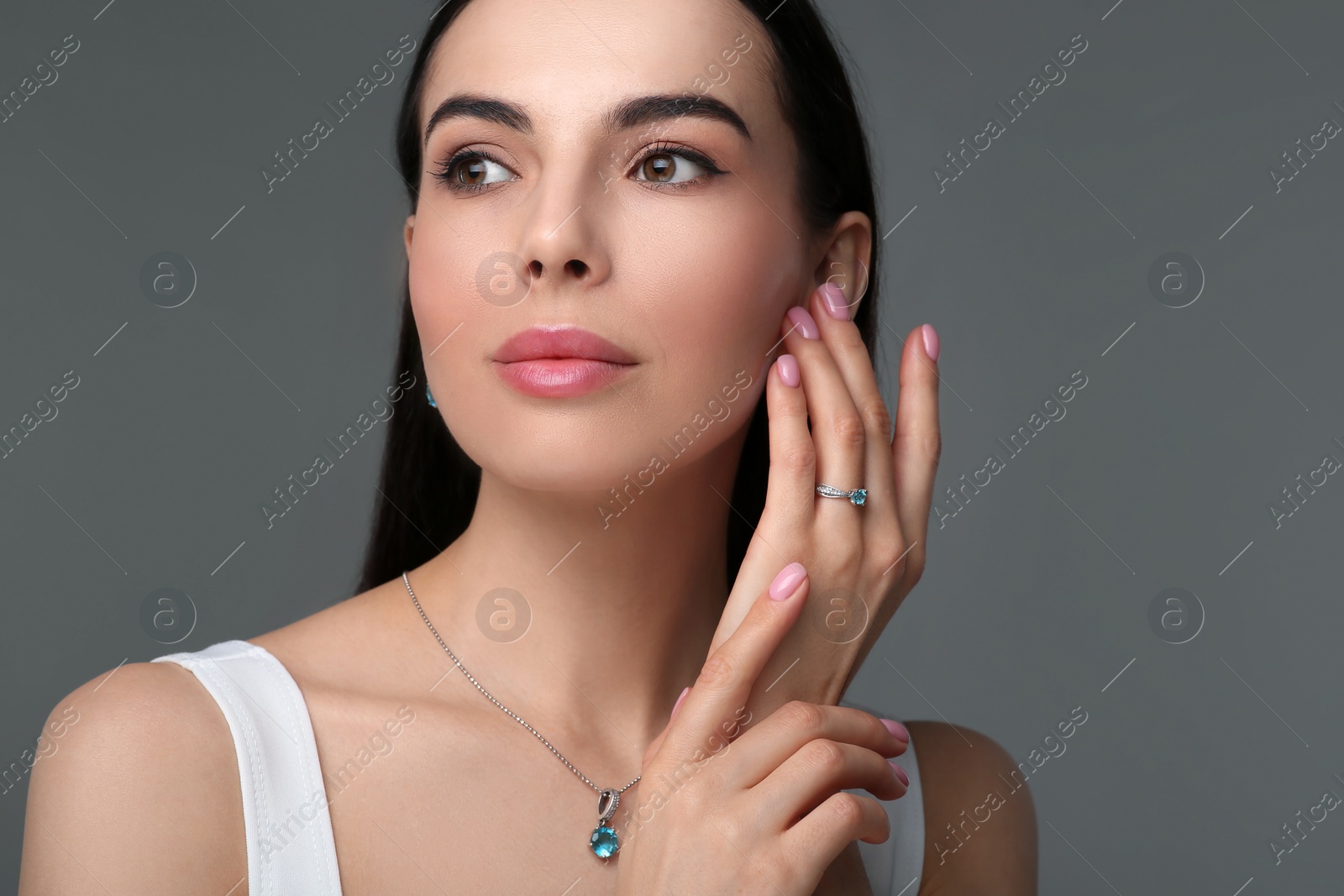 Photo of Beautiful young woman with elegant jewelry on dark grey background