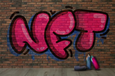 Brick wall with graffitied abbreviation NFT and spray paint cans