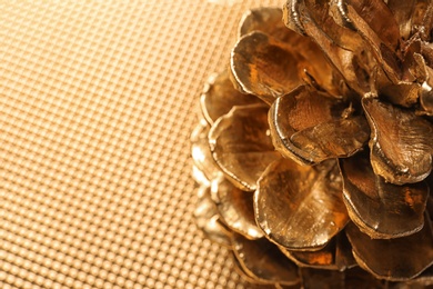 Photo of Golden pine cone on blurred background, closeup view with space for text