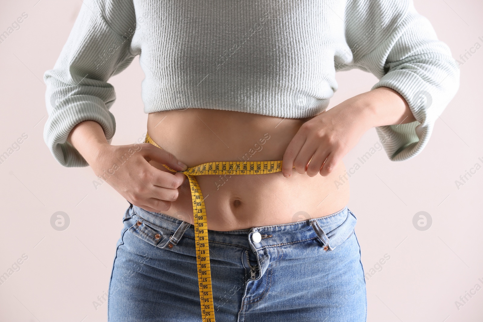 Photo of Woman with measuring tape on white background, closeup. Overweight problem after New Year party