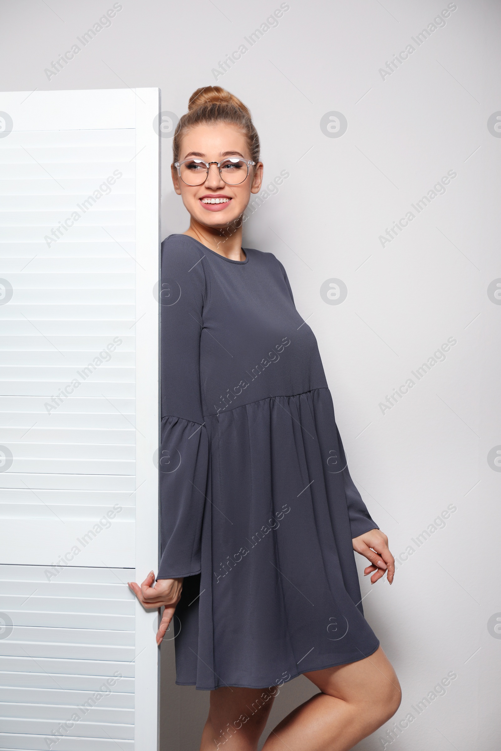 Photo of Young woman near folding screen against light background. Dressing room