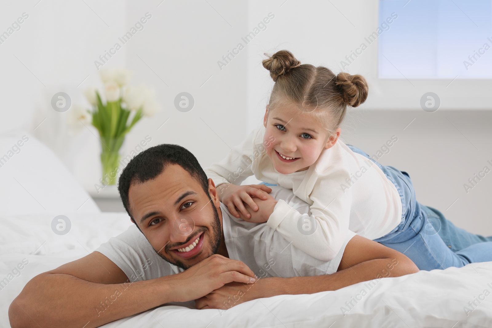 Photo of Little girl with her father on bed at home. International family