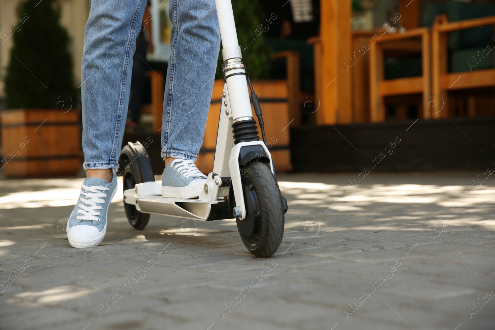 Photo of Woman riding electric kick scooter outdoors, closeup. Space for text