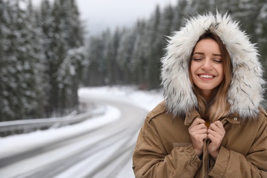 Young woman in warm clothes outdoors, space for text. Winter vacation