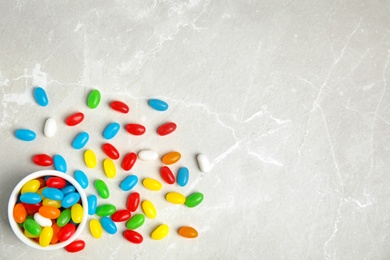 Flat lay composition with bowl of jelly beans on light background. Space for text