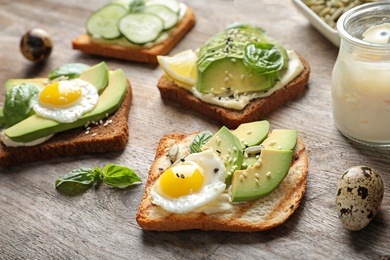 Photo of Toast bread with fried eggs, avocado and cucumber slices on wooden table