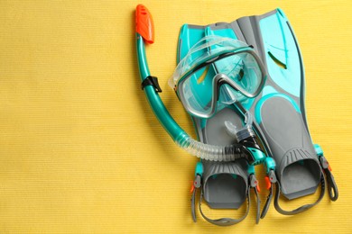 Photo of Pair of flippers, snorkel and diving mask on yellow background, flat lay