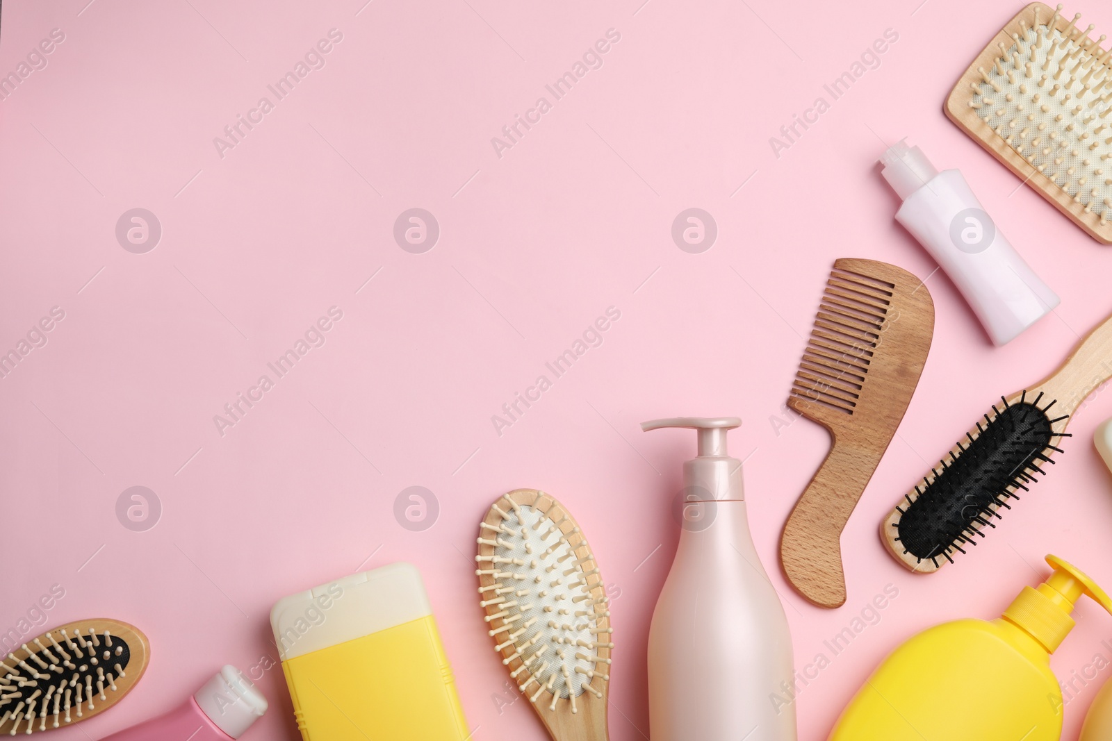Photo of Flat lay composition with hair cosmetic products and tools on pink background. Space for text