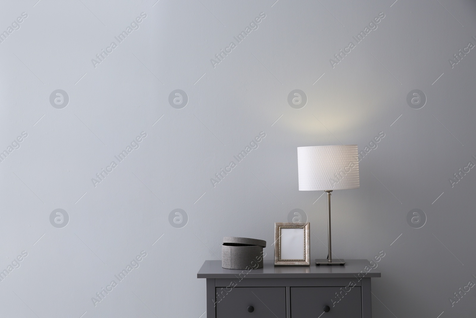 Photo of Modern grey chest of drawers near light wall in room, space for text. Interior design