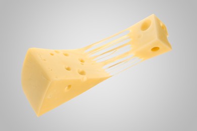 Tasty cheese stretching in air on grey background