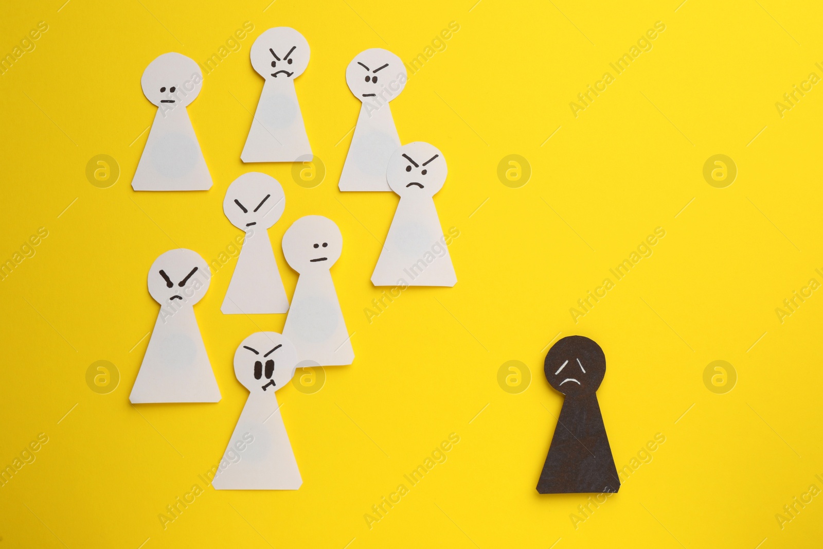 Photo of Black paper pawn standing out from white ones on yellow background, flat lay. Concept of racism