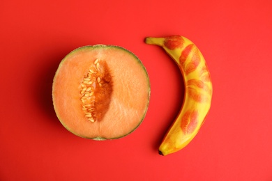 Photo of Flat lay composition with fresh banana and melon on red background. Sex concept