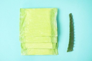 Photo of Flat lay composition with menstrual pads and aloe leaf on color background. Gynecological care