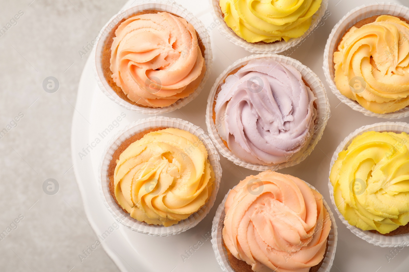 Photo of Stand with tasty cupcakes on light table, top view