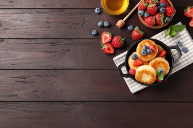 Photo of Delicious cottage cheese pancakes with fresh berries and honey on wooden table, flat lay. Space for text