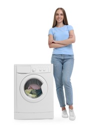 Beautiful young woman near washing machine with laundry on white background