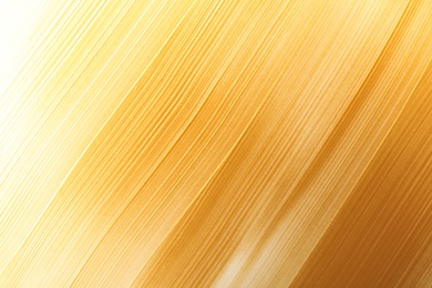 Photo of Strokes of gold paint as background, top view