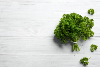 Photo of Fresh curly parsley on white wooden table, flat lay. Space for text