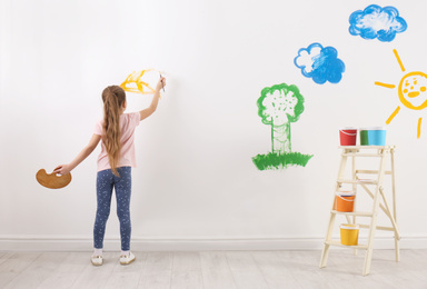 Photo of Little child painting on white wall indoors