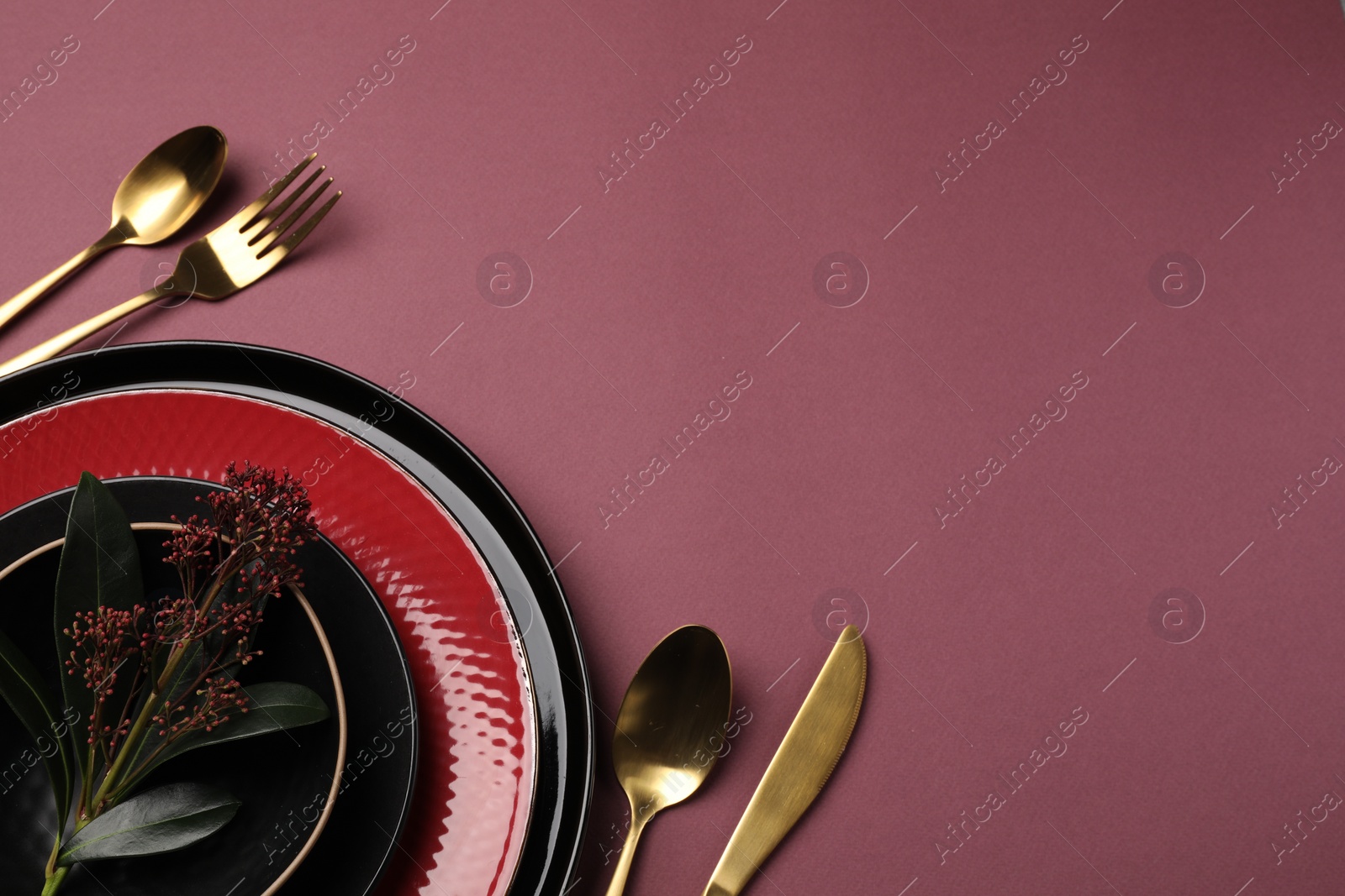 Photo of Stylish table setting with cutlery and floral decor on pink background, flat lay. Space for text