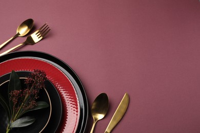 Stylish table setting with cutlery and floral decor on pink background, flat lay. Space for text